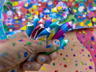 Close-up of handful of open multi colored paint tubes  