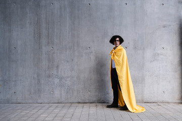 Man wearing yellow cape standing in front of gray wall