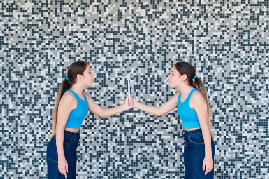 Girls with wind turbine model standing in front of wall
