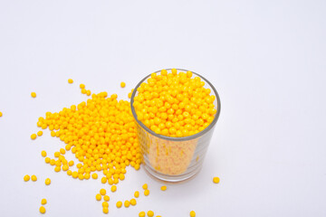 yellow masterbatch granules in a shot isolated on a white background, this polymer is a colorant...