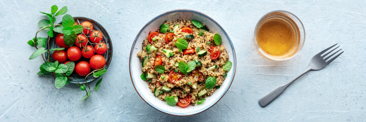 Quinoa tabbouleh salad in a bowl panorama, a healthy dinner with tomatoes and mint, overhead flat...