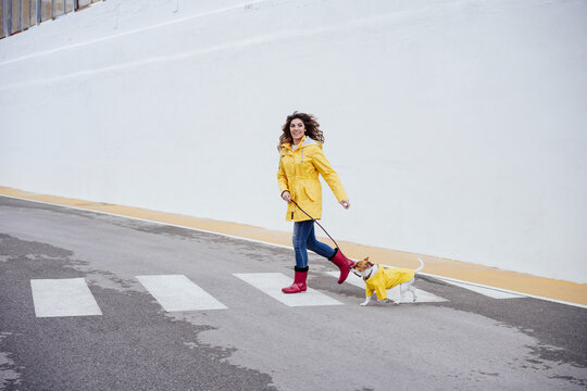 Playful woman running with dog on crosswalk