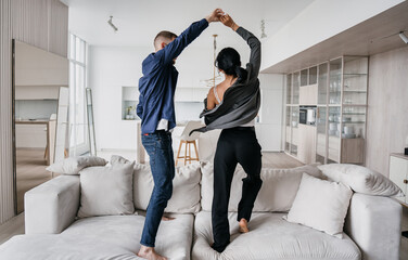 Joyful couple dancing at home, expressing happiness and love.