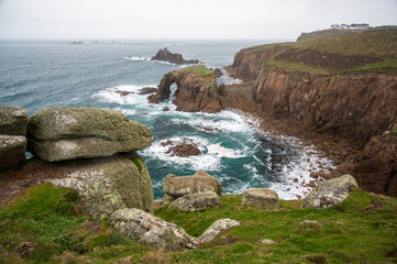 Enys Dodnan Arch with rough seas during a storm at Land's End in Celtic Sea, Penzance, Cornwall. 