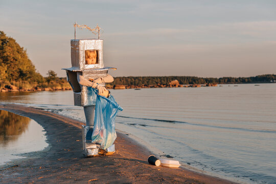 Boy in astronaut costume cleans up garbage by sea at beach