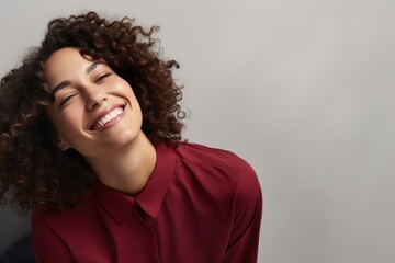 Fototapeta na wymiar A happy woman with curly hair wearing a red shirt smiles at the camera.
