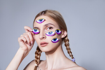 Young woman with braided hair with eyes stickers on face at studio