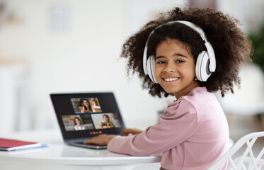 Cute little african american girl attending online lesson from home