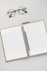 a notebook with sheets in a line on a light background. metal-rimmed glasses. free space for text