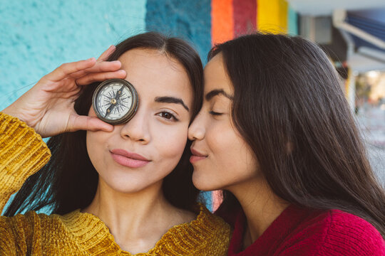 Young woman covering eye with compass by twin sister