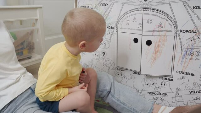 mother with child playing with house cardboard coloring playhouse, little boy drawing on wall of carton house toy for children, kid having fun at home.