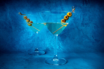 Martini. Two glasses of dirty martini cocktails with vermouth and olives, aperitif, on a blue...