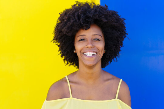 Cheerful young woman in front of two tone color wall
