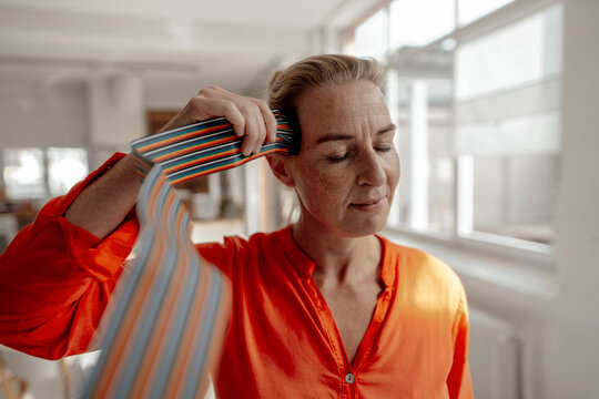 Businesswoman with eyes closed touching computer cables to head at office