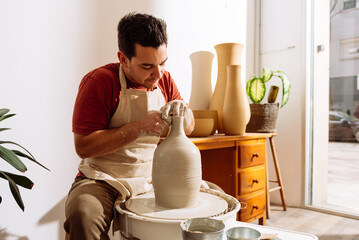 Man making clay vase in pottery workshop