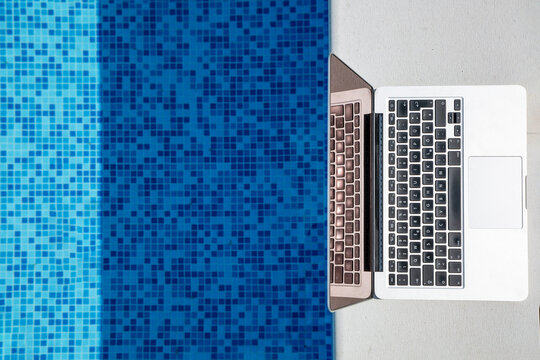 Laptop kept near swimming pool on sunny day