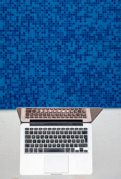 Laptop kept near blue swimming pool on sunny day
