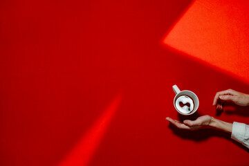 Hands of woman with tea cup over red table