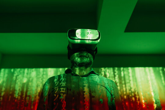 Man wearing virtual reality simulator in front of falling digital code