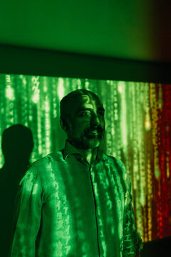 Digital code falling on smiling mature man in front of wall