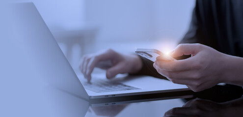 Close up of woman hand using mobile phone for online shopping and digital payment via mobile banking app. Business woman using smartphone while working on laptop computer on office table