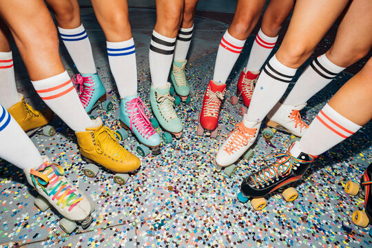 Legs of women wearing roller skates over confetti