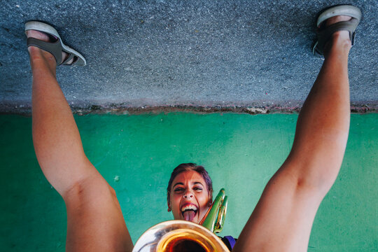 Playful woman sticking out tongue bending in front of wall