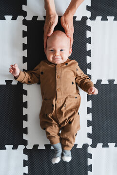 Smiling baby boy lying on mat at home