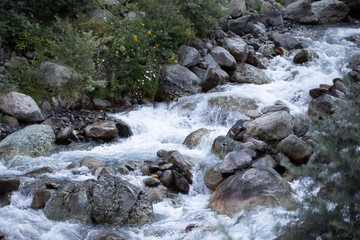 Mountain river against the background of scattered large stones and boulders.