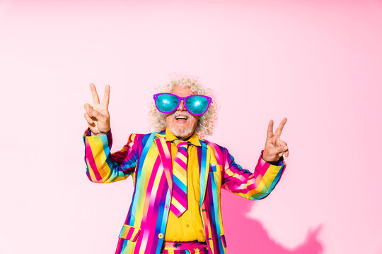 Happy senior man wearing oversized sunglasses and gesturing peace sign