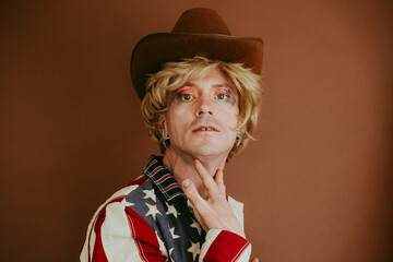 Drag queen wearing hat against brown background
