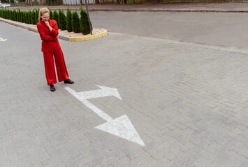 Thoughtful woman with hand on chin standing near arrow sign at street