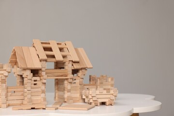 Wooden entry gate and building blocks on white table against grey background, space for text. Children's toy