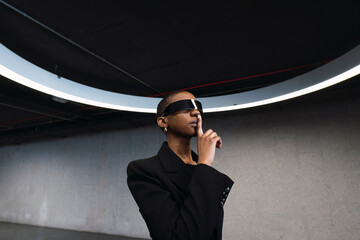 Young woman with finger on lips using futuristic glasses in parking garage
