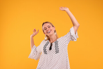 Portrait of smiling hippie woman dancing on yellow background