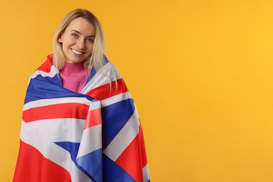 Happy woman with flag of United Kingdom on orange background, space for text