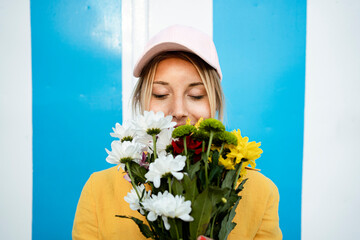 Beautiful woman with eyes closed smelling flower bouquet