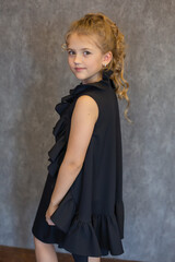 Fototapeta premium blonde girl with a ponytail on her head in a beautiful black dress on a black background