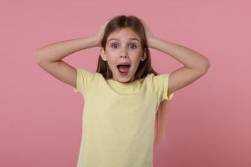 Portrait of surprised girl on pink background