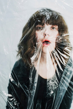 Depressed woman suffocating behind plastic