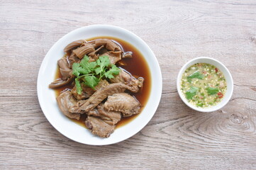 chop boiled duck wing and stew intestine in brown soy soup on plate dipping spicy sauce 