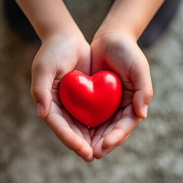 A top-view photographic image of hands holding a red heart, symbolizing health care The bright red heart contrasts with a gentle background Created Using overhead photography, vivid red color,