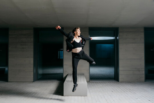 Non-binary young man wearing black suit dancing in basement