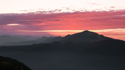 Obraz premium Silhouettes of mountains in golden sunset. Moving clouds in orange sky. Warm winter mountain scenery in northern Taiwan, Shuangxi Buyanting Pavilion.