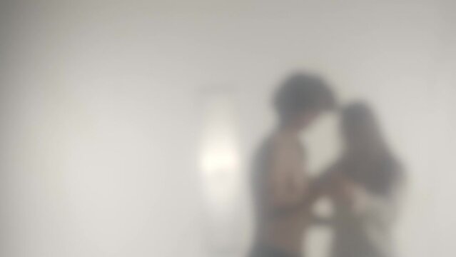 Blurred silhouette of a couple dancing a waltz behind a transparent frosted glass or curtain. Concept of ghosts and spirits, the afterlife and the otherworld. HDR BT2020 HLG Material.