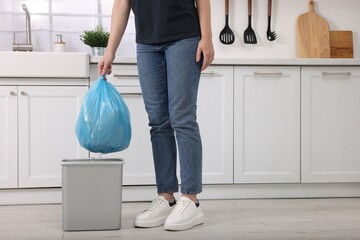 Woman taking garbage bag out of trash bin in kitchen, closeup - obrazy, fototapety, plakaty