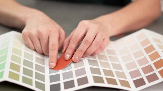 The designer selects the colors according to the palette for the future project. Close-up of the hands.