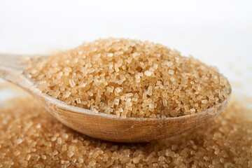 Wooden spoon with brown sugar on white background