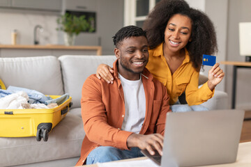 black couple using laptop and credit card buying tickets indoor