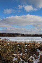 Obraz premium A body of water with grass and rocks and trees on the side